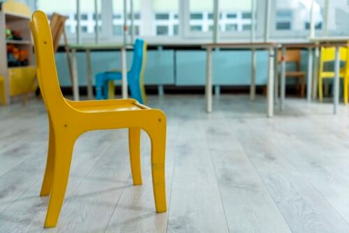 Empty yellow children's chair in a classroom, representing childhood, education, and learning environments